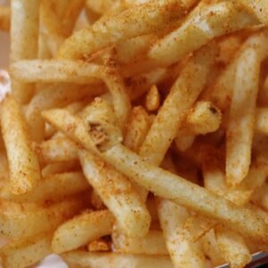 Tasty and crispy seasoned French fries in a paper box, perfect for a snack.